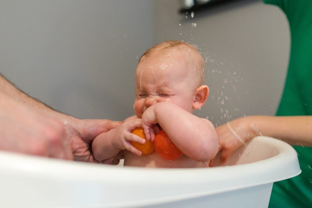 mother splashing with water her baby in bath tub
mamagare paketi poklon paket