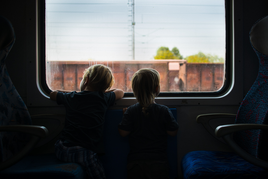 two boys riding on a train watching through window