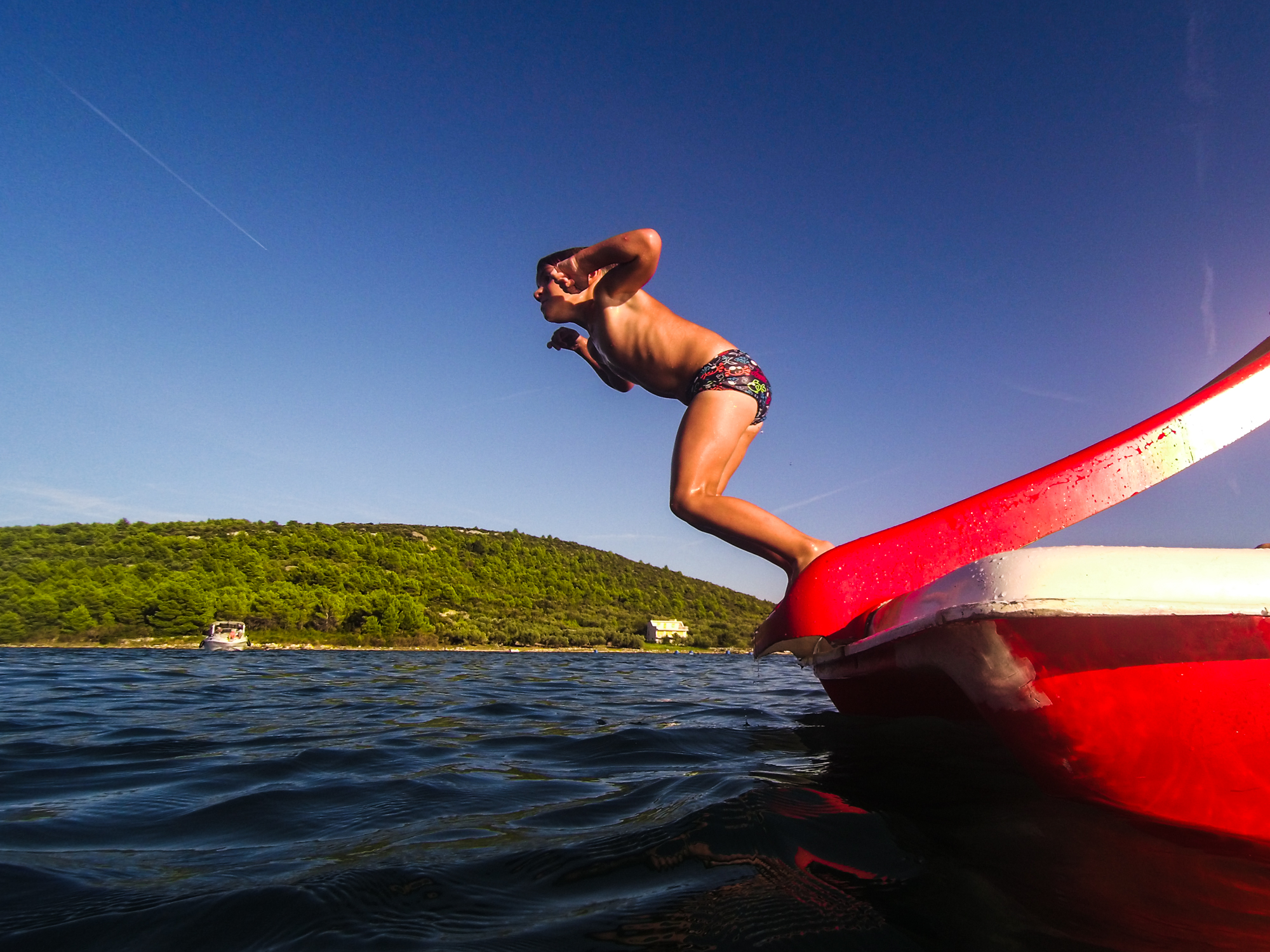 boy jumping into the sea from a red paddle boat Croatia