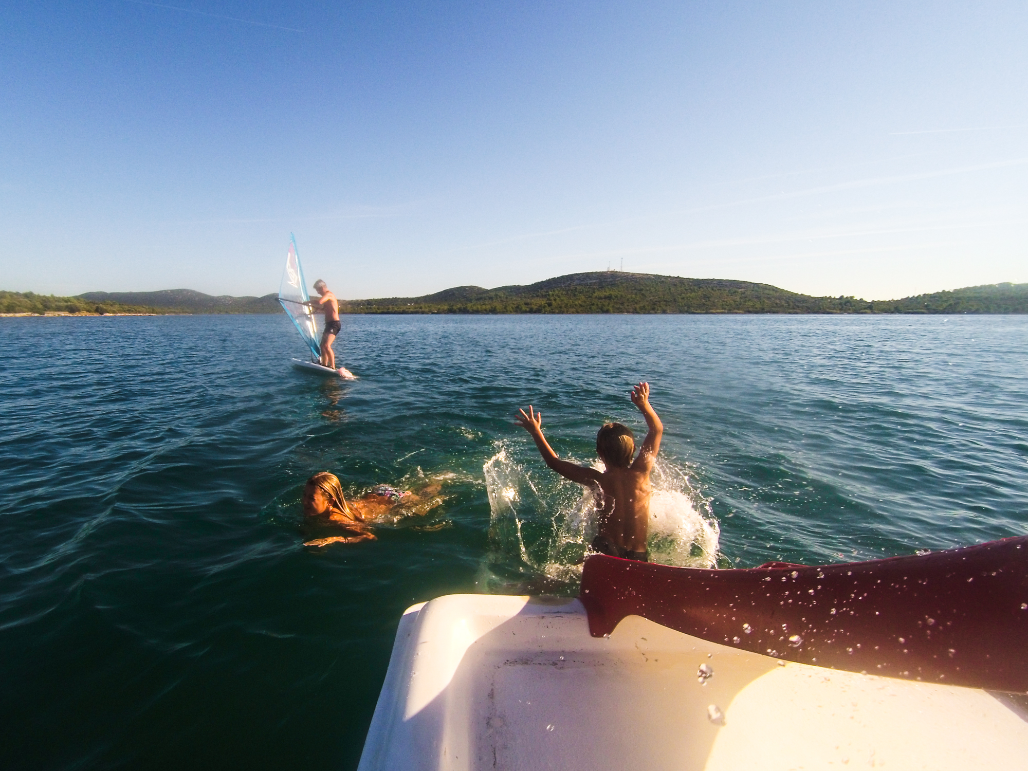 on a paddle boat in the sea three people one surfing one swimming one sliding down the toboggan Croatia