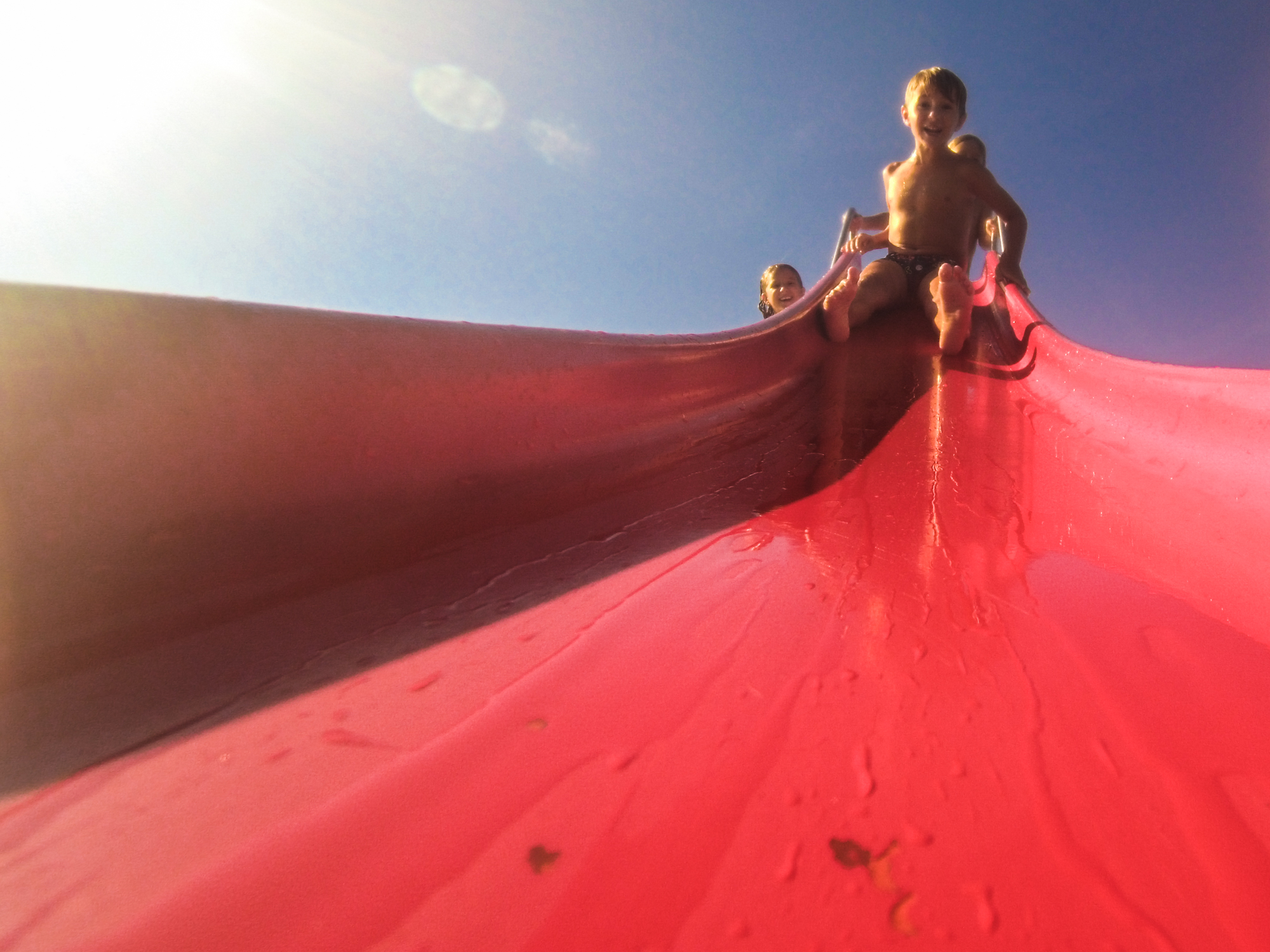 little boy on top of red paddle boat toboggan preparing to slide down into the sea Croatia