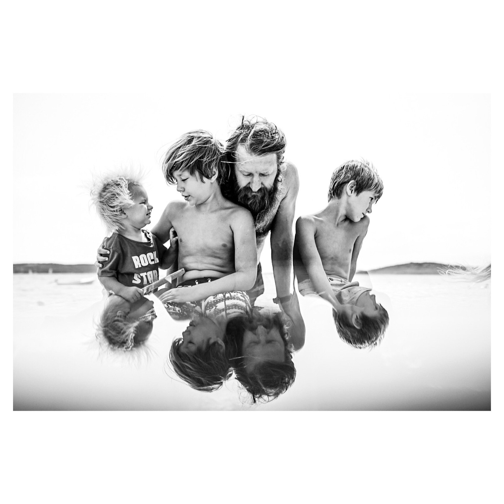 black and white photo of dad with three sons reflection
