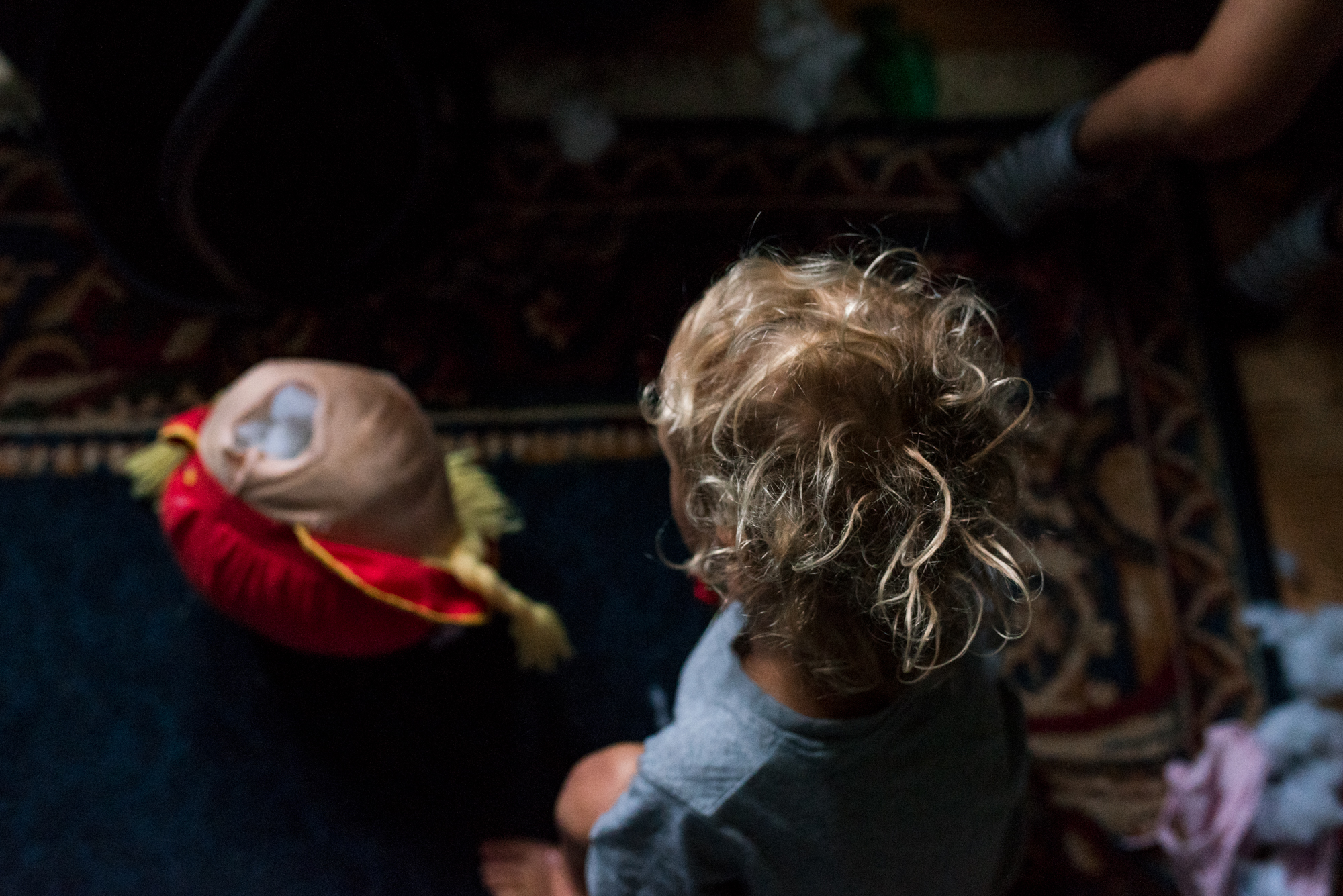Obiteljska-dokufotografija-Zagreb-curly boy looking down the broken head of a doll