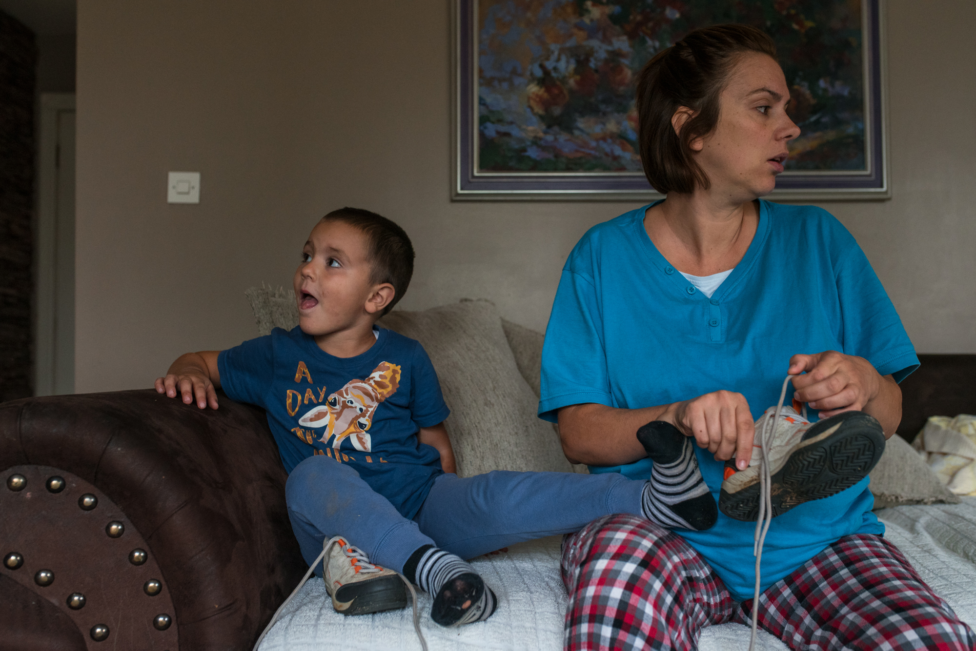 Obiteljska-dokufotografija-Zagreb-boy and mom looking opposite directions mom putting shoes on boy not cooperating